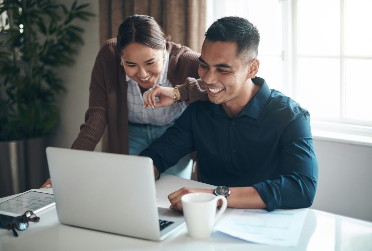 Happy with how their finances are looking shot of a young couple using a laptop together at home .jpg