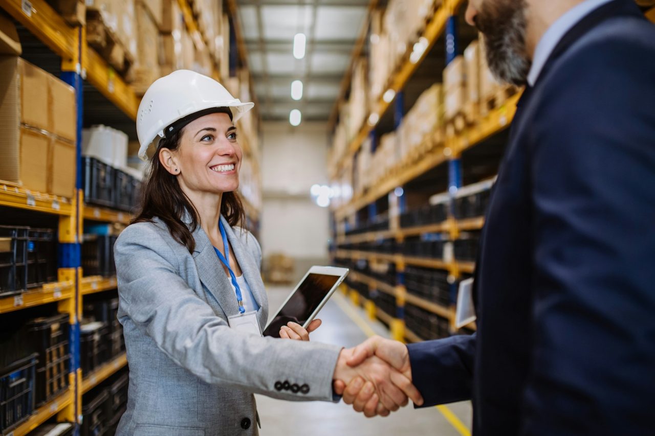 Managers in suits shaking hands in warehouse .jpg